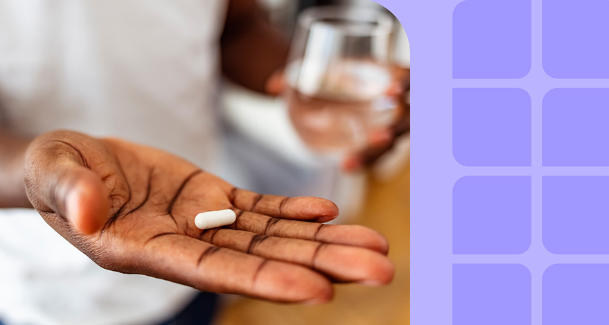 Person holds out a pill in their hand.