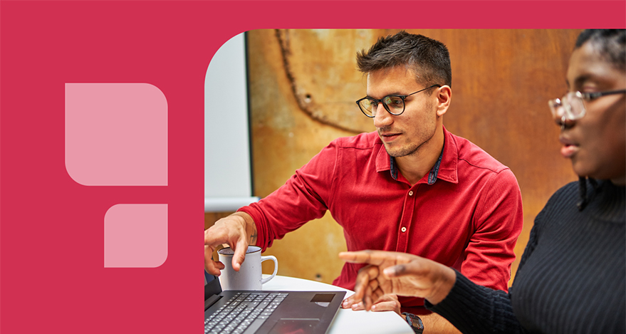 A person works at a computer with another person. Both individuals point at the computer screen.