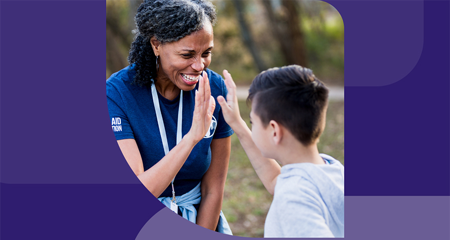 Two people high five outdoors.