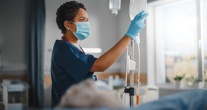 A nurse places an IV bag in its proper position while a patient lies down.