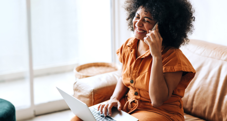A woman works from home and works on her laptop while making a phone call